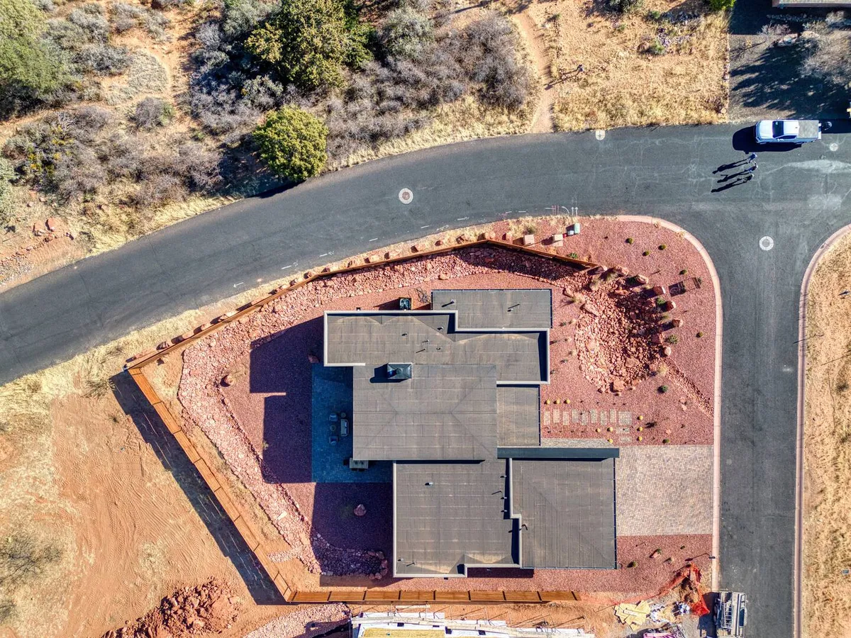 A striking exterior shot of the property's modern architectural design, set against a beautifully landscaped yard and surrounded by Sedona’s iconic red rock terrain. The scene is peaceful and welcoming, inviting guests to take in sunsets or explore the natural environment just beyond the yard.