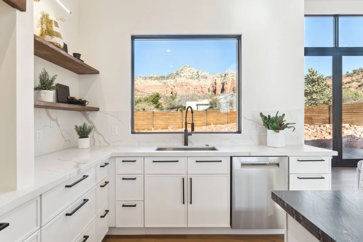 This modern kitchen scene centers on a sleek countertop and faucet, with a large window framing an impressive mountain view. The design emphasizes clean lines and ample counter space, creating a serene atmosphere ideal for both casual cooking and entertaining. The combination of high-end finishes and natural light showcases the kitchen as a culinary haven.